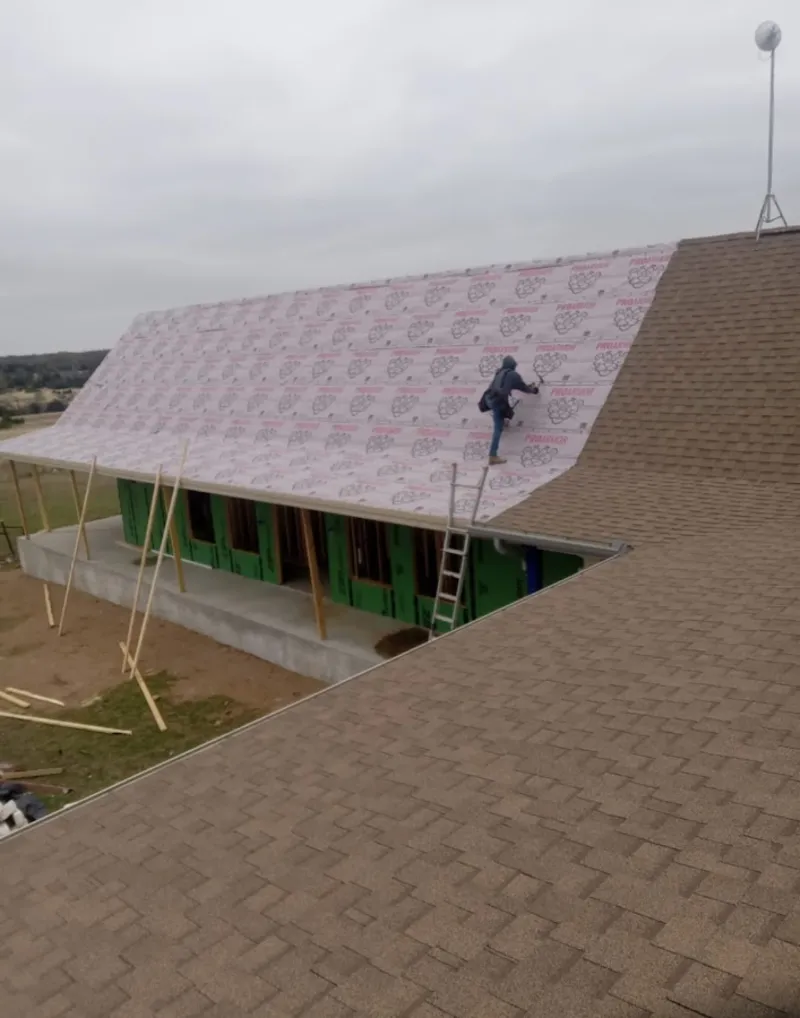 Worker preparing underlayment for a metal roof installation in Triangle